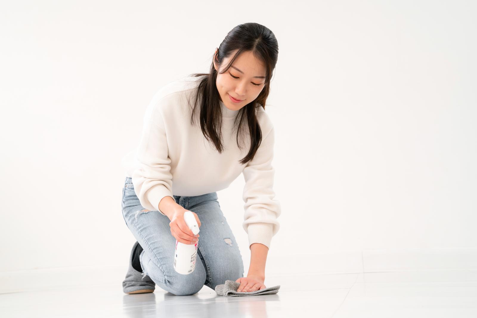 床に洗剤を噴きかけながら掃除する女性が雑巾を持つ［モデル：SAKI］