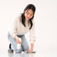洗剤を床に噴きかけて掃除する女性のハウスクリーニングの写真