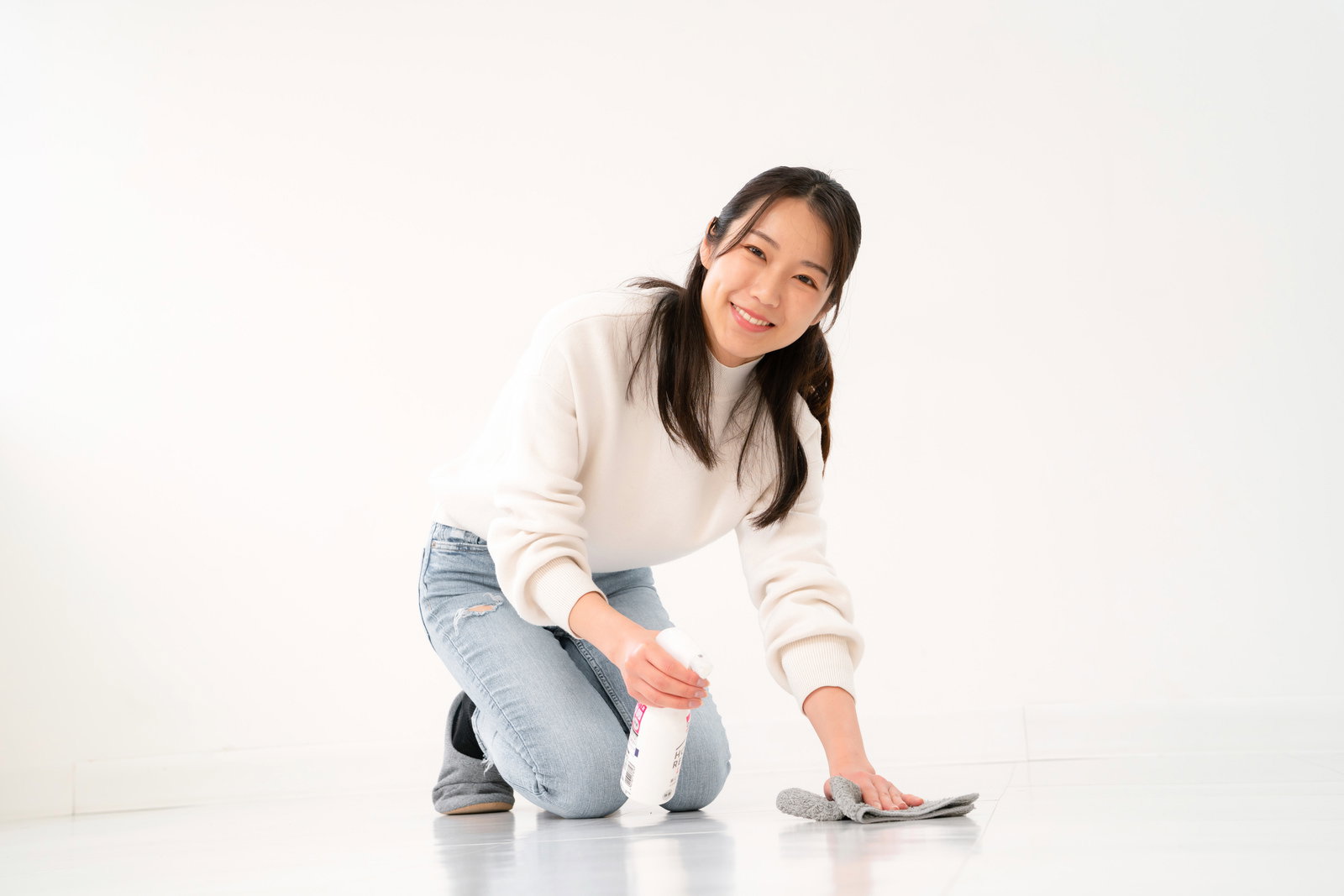 床をスプレーと布巾で拭き掃除する笑顔の女性［モデル：SAKI］