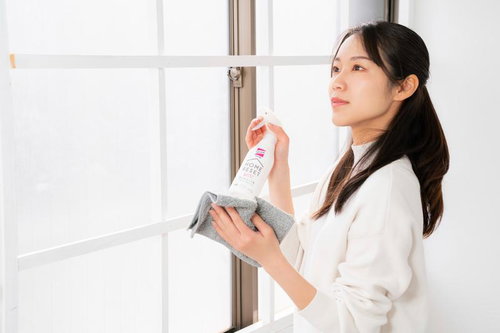 スプレーボトルでガラス拭きをする女性の窓ガラス清掃作業