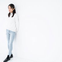 白背景で横向きに立つ不安げな女性のポートレートの写真