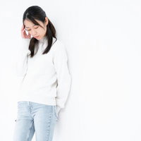 頭痛で伏し目がちに手を当てる女性の写真
