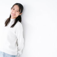 壁に寄りかかってお礼を言う女性の写真