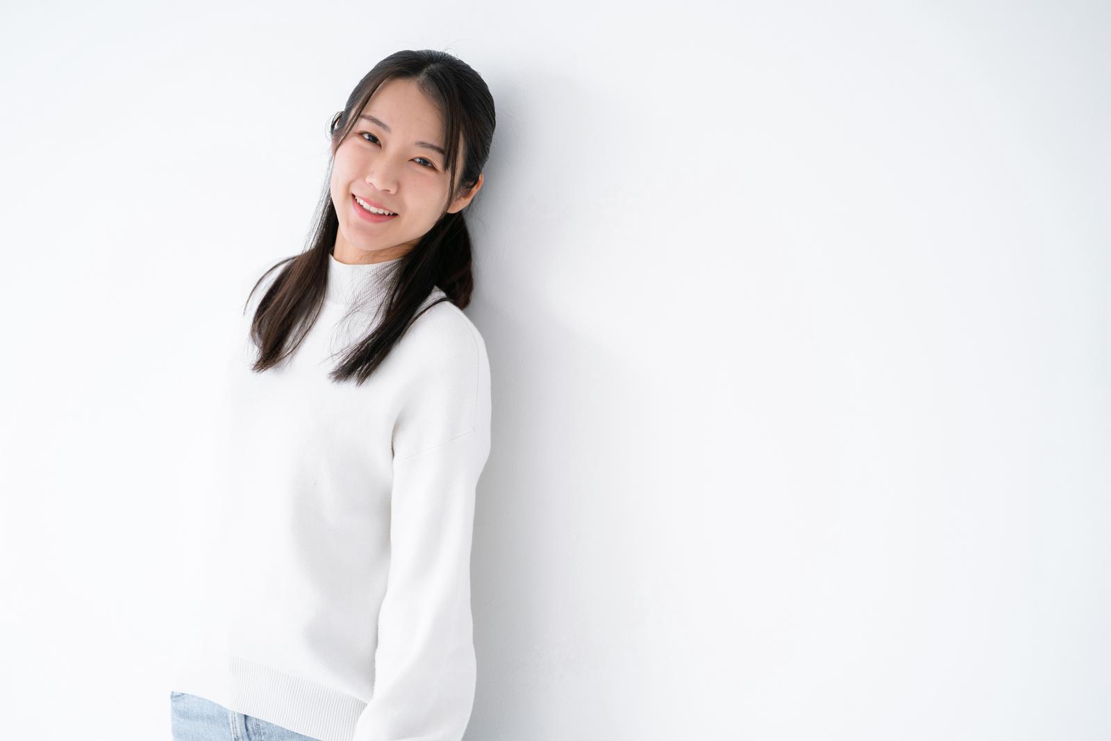 白ニットを着た女性が白背景で微笑むポートレート写真［モデル：SAKI］