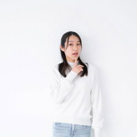 驚きのリアクションをする白い長袖の女性の顔と仕草の写真