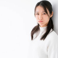 拗ねた表情で壁にもたれる女性の写真