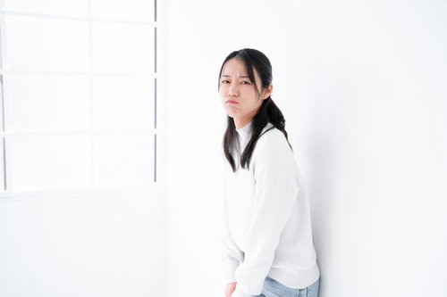 白いパーカーでご機嫌ななめの表情を見せる女性