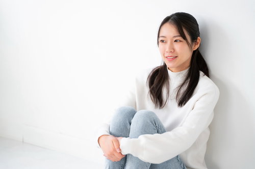 壁に寄りかかって座る女性