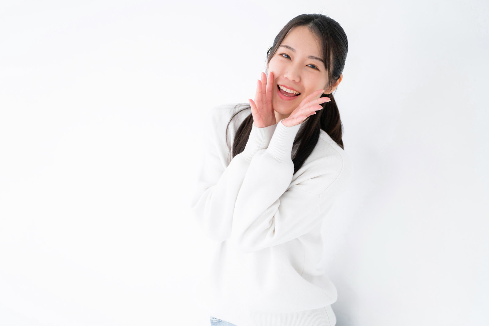白い服を着た女性が両手を頬に添えて笑顔でエールを送るポーズ［モデル：SAKI］