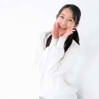 白い服で両手を頬に添えて笑顔でエールを送る女性の写真