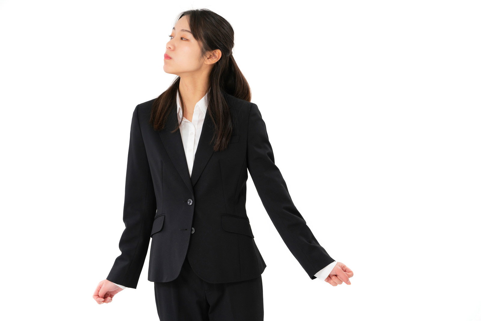 黒いスーツを着て不機嫌な表情で両手を広げる女性社員［モデル：SAKI］