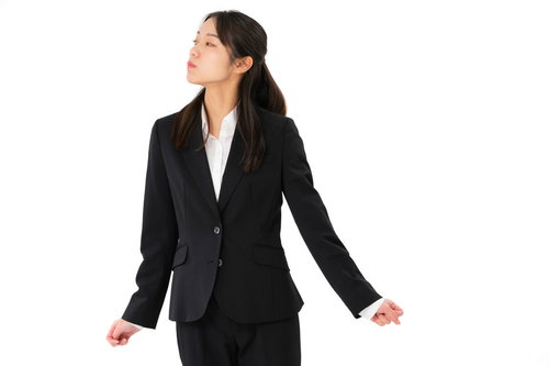 不機嫌な表情で両手を広げる女性社員、ビジネスストレスを表現