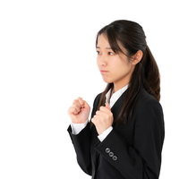 グッと我慢するスーツ姿の女性社員の写真