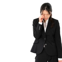 成果がでないで落ち込み泣く黒いスーツの女性社員の写真