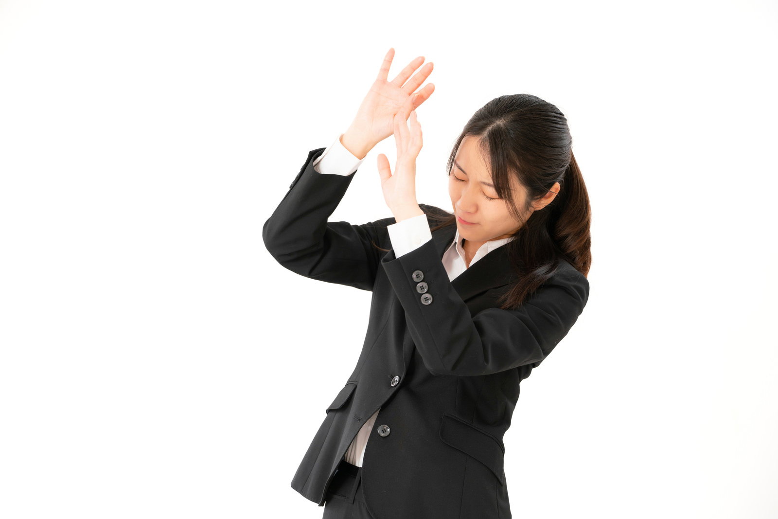 手で顔を覆い恐怖を表現する黒いスーツ姿の女性会社員［モデル：SAKI］
