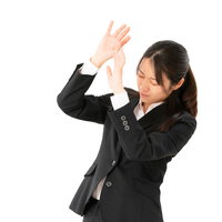 パワハラに押しつぶされそうな黒いスーツの女性社員の写真