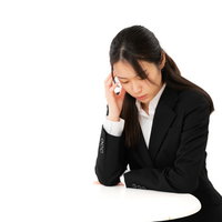 頭を抱えて案件ばかりで苦悩する女性社員のストレス表現の写真