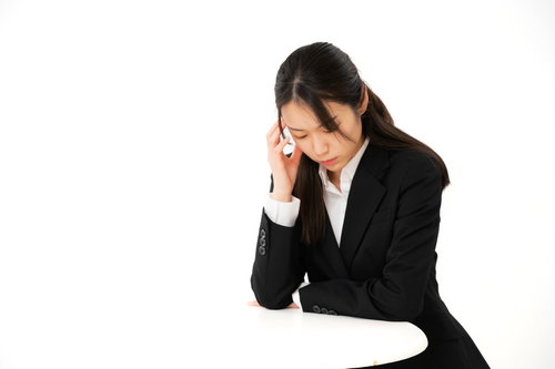 頭を抱えて案件ばかりで苦悩する女性社員のストレス表現