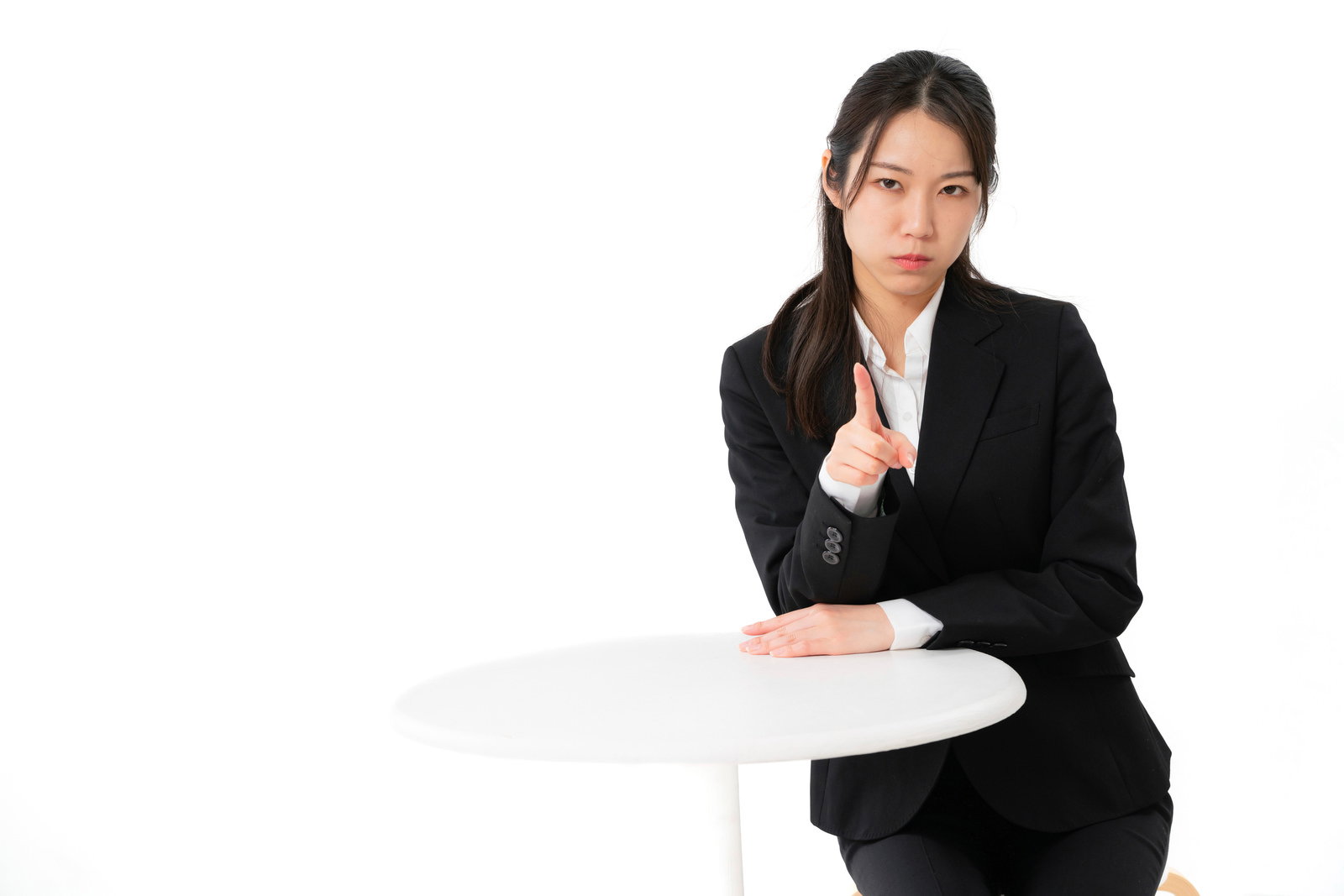 黒いスーツを着た女性が人差し指を立てて指摘するポーズ［モデル：SAKI］