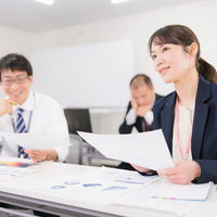 和やかな雰囲気で進む職場ミーティングで資料を確認する女性の写真