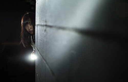 ハンドライトで照らしながら恐る恐る暗闇を探索する女性