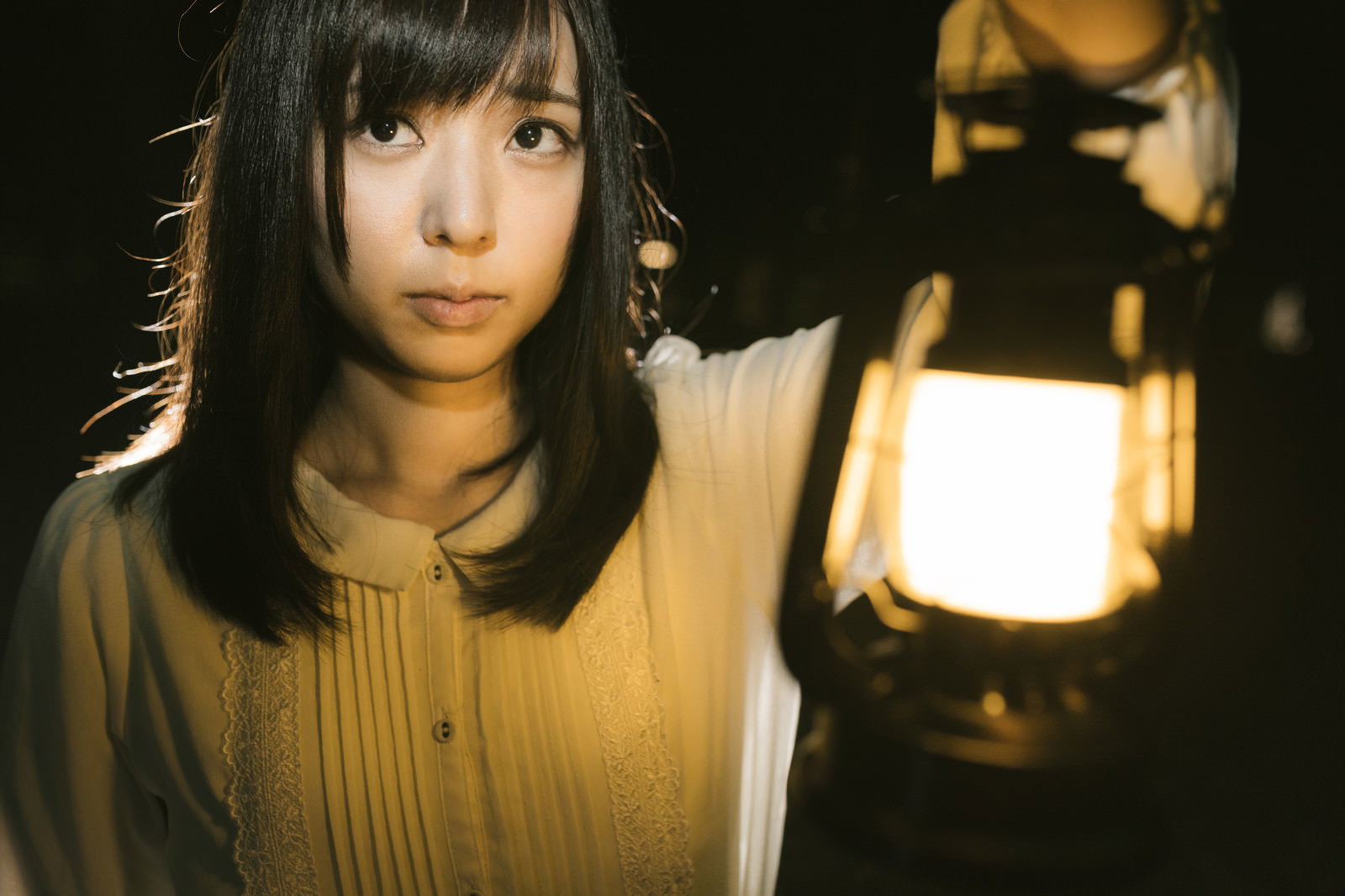 ランタンを手に持ち、暖かな光に照らされた女性［モデル：さとうゆい］