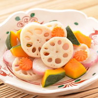 白い器に盛り付けたれんこんと野菜の煮物、竹の子と花型にんじんの写真