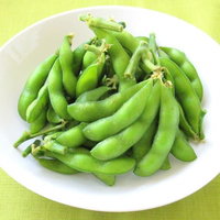 白い皿に盛られた枝つき枝豆のビール用おつまみの写真