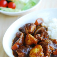 白い皿に盛られたカレーとサラダの定食、ご飯付きの写真