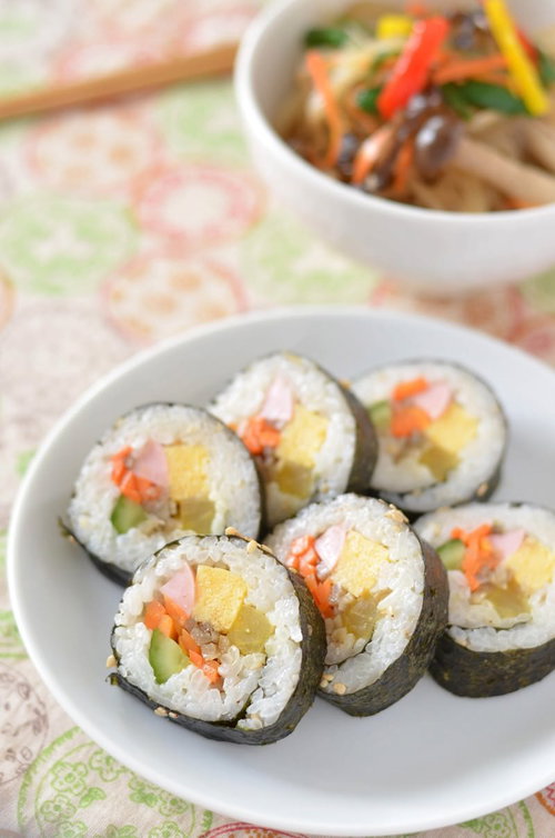 具だくさんの海苔巻きとビビンバの食卓、卵焼きとキュウリ入り