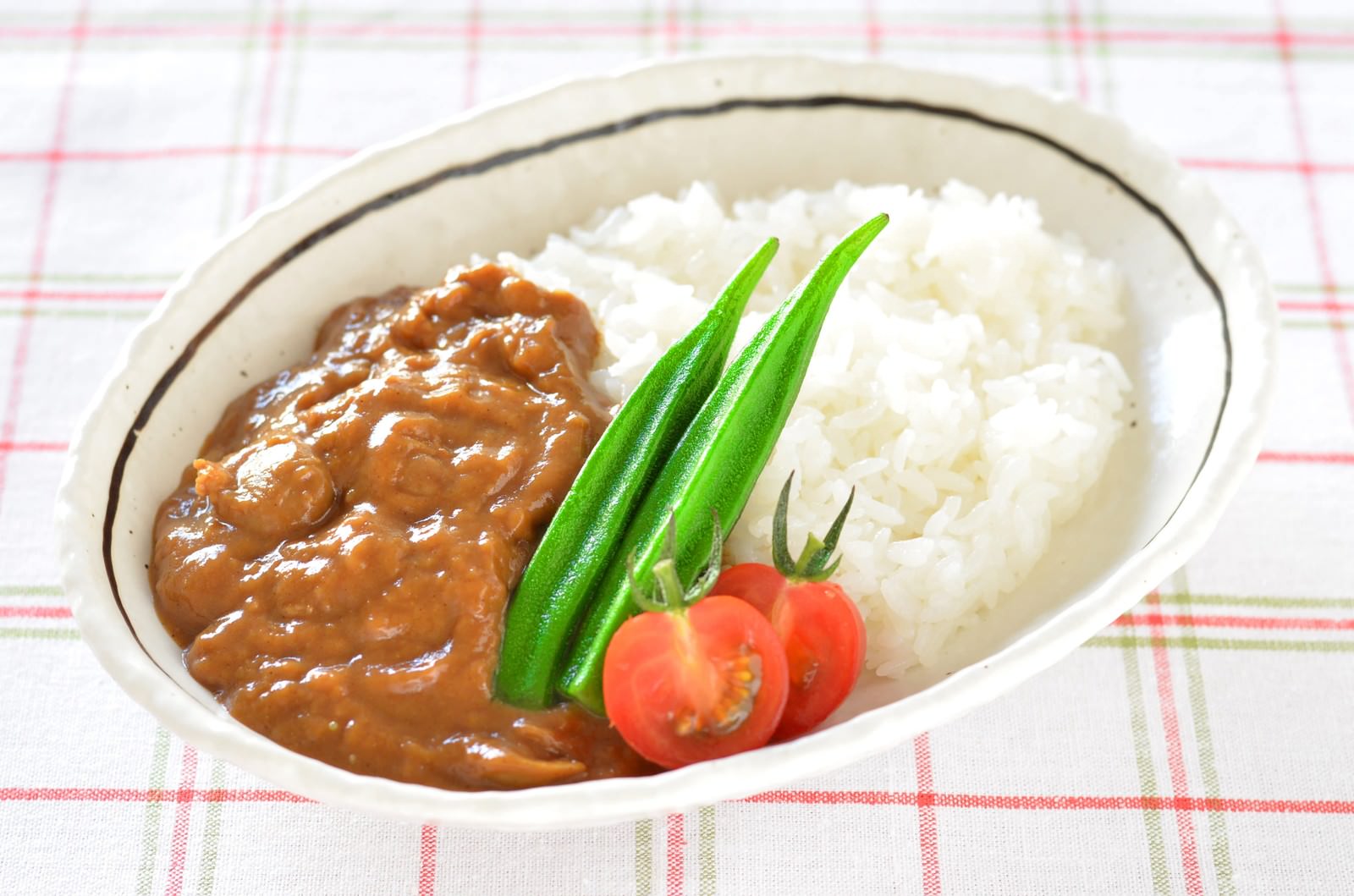 白い楕円皿に盛られたオクラとトマト入りカレーライス