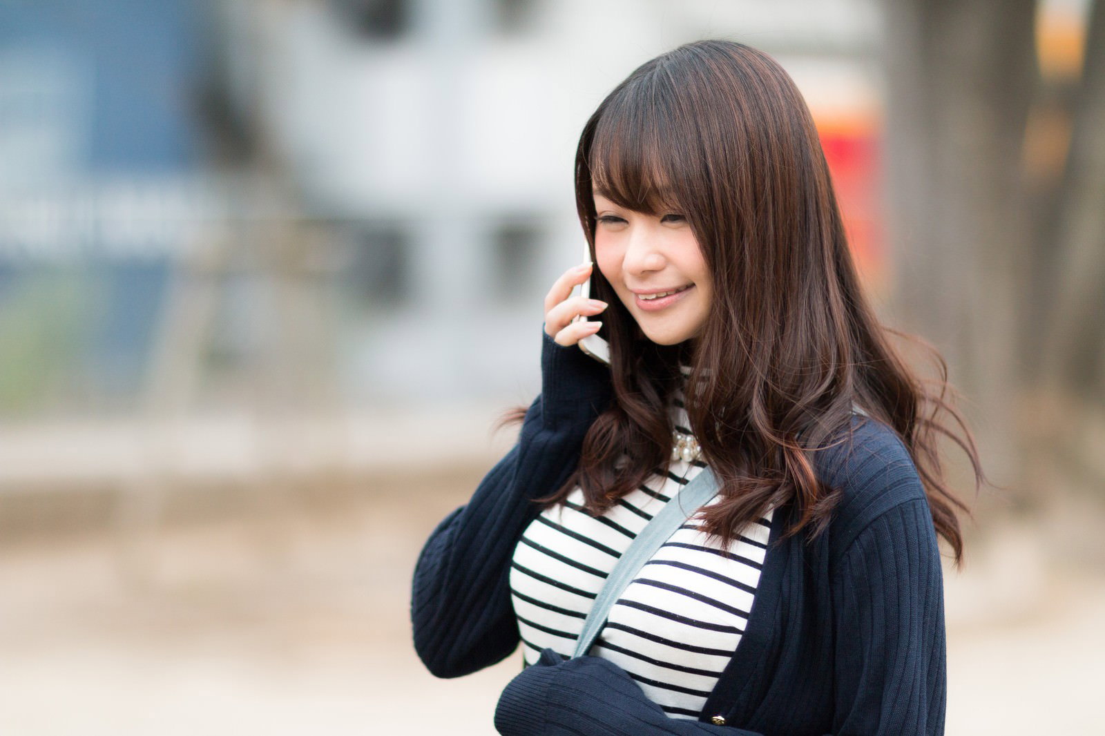 スマートフォンで通話する笑顔の女性［モデル：茜さや］