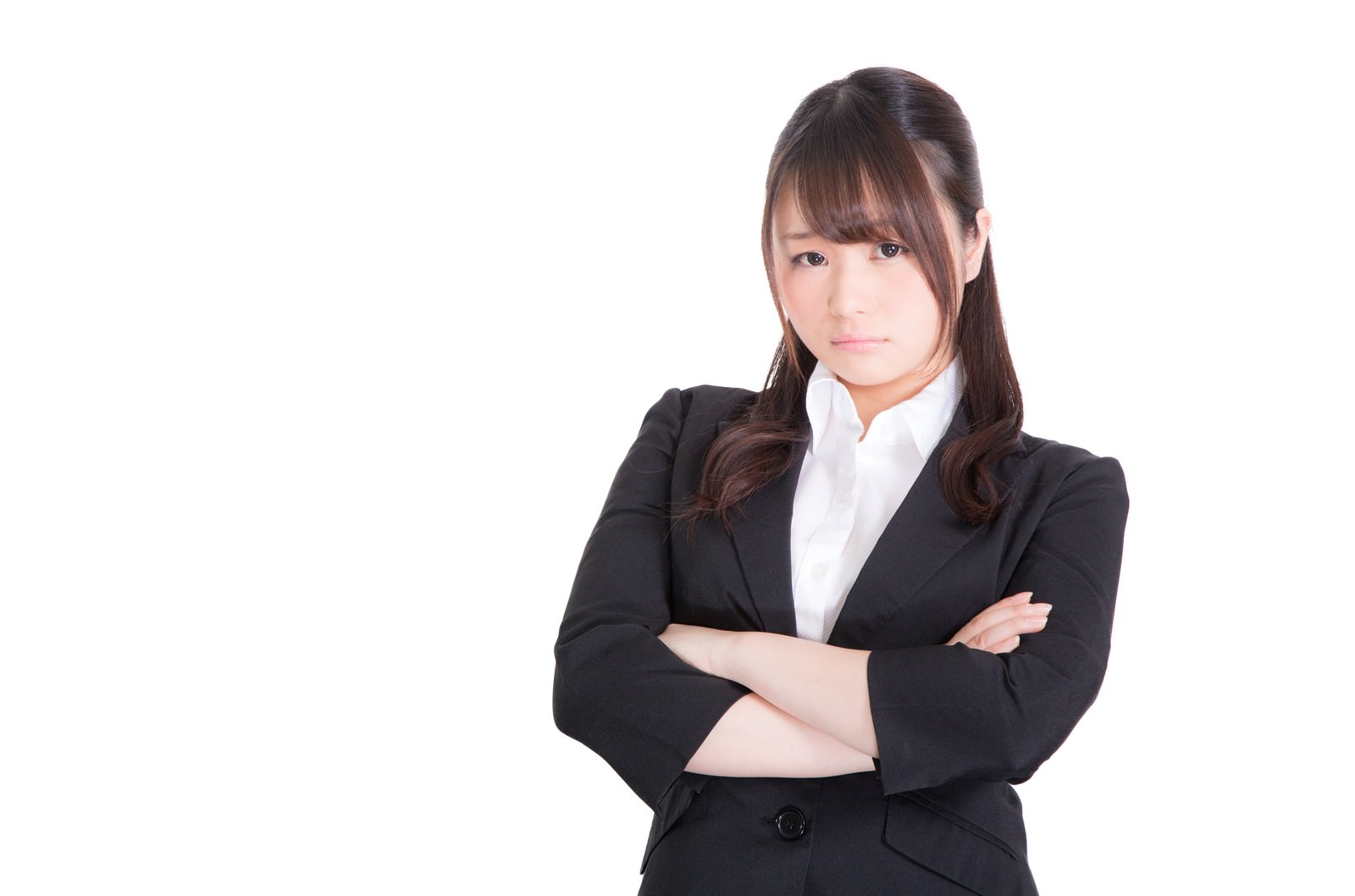 腕を組んで考え込む、ムスッとした表情のスーツ姿の女性［モデル：茜さや］