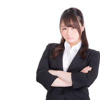 ムスッとした表情で腕を組む、考えるリクスー女子の写真