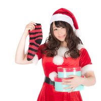 赤と白のサンタ衣装で靴下とプレゼントを持った女性の写真