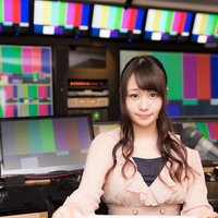 放送終了後のカラーバーの前でニュースを放送する女性アナウンサーの写真