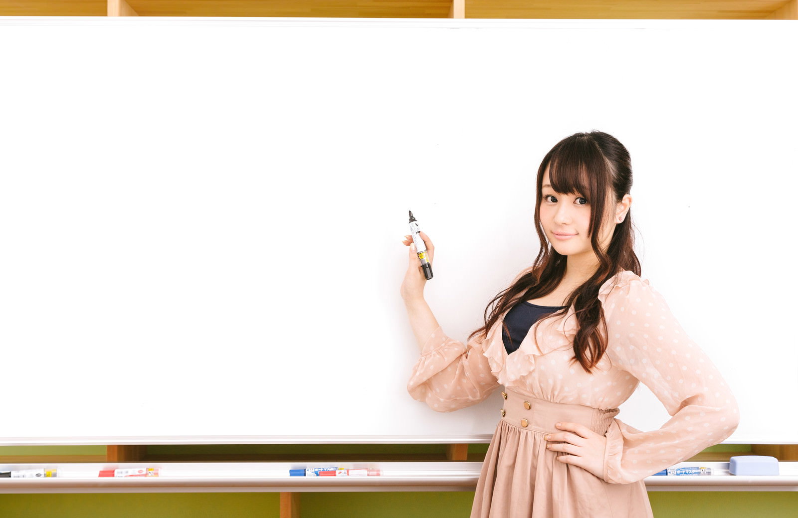 ホワイトボードの前でマーカーを持つ女性［モデル：茜さや］