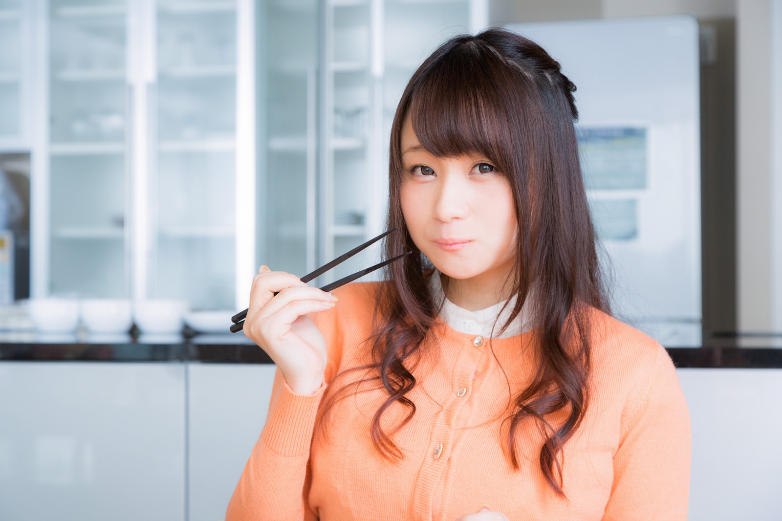 箸を持ち笑顔で食レポする女性アナウンサー［モデル：茜さや］
