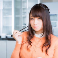 笑顔で美味しさを表現する食レポ中の女性アナの写真