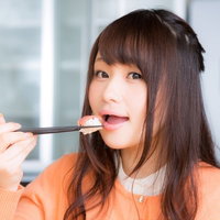 一口サイズのお寿司を箸で頬張る女性、食レポ撮影の写真