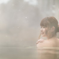 雪が降る平湯温泉の雪見露天風呂で入浴する女性の写真