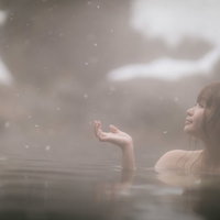 粉雪が舞う雪見露天風呂で静かに入浴する女性の写真