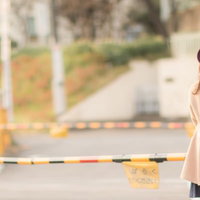 踏切で赤信号を待つスマートフォンを持つ女性の写真