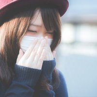 花粉症でくしゃみが止まらないマスクをした女性の写真
