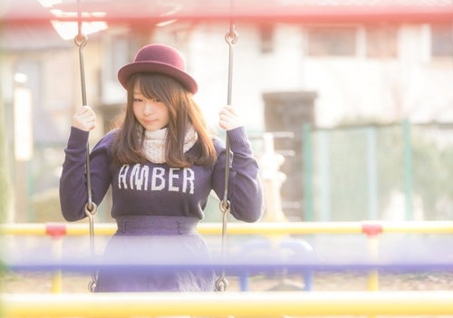 公園のブランコで揺られているピンク帽子の女性