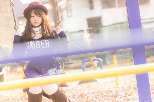 ブランコの柵が邪魔です。紫のスウェットを着た女性