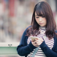 待ち合わせ場所をスマホで確認するカジュアルな女性の写真