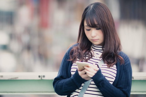 待ち合わせ場所をスマホで確認するカジュアルな女性