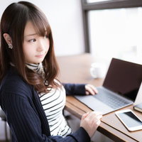 カフェでノマド作業をする女性とノートパソコンの写真