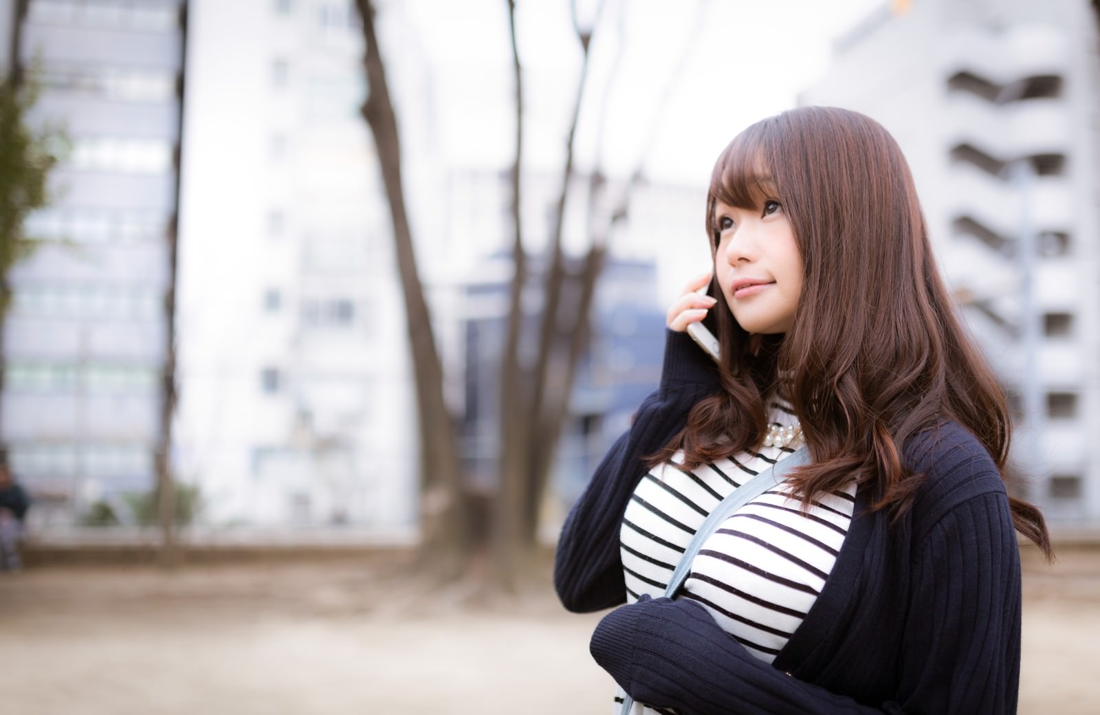 スマートフォンで通話しながら歩く女性［モデル：茜さや］
